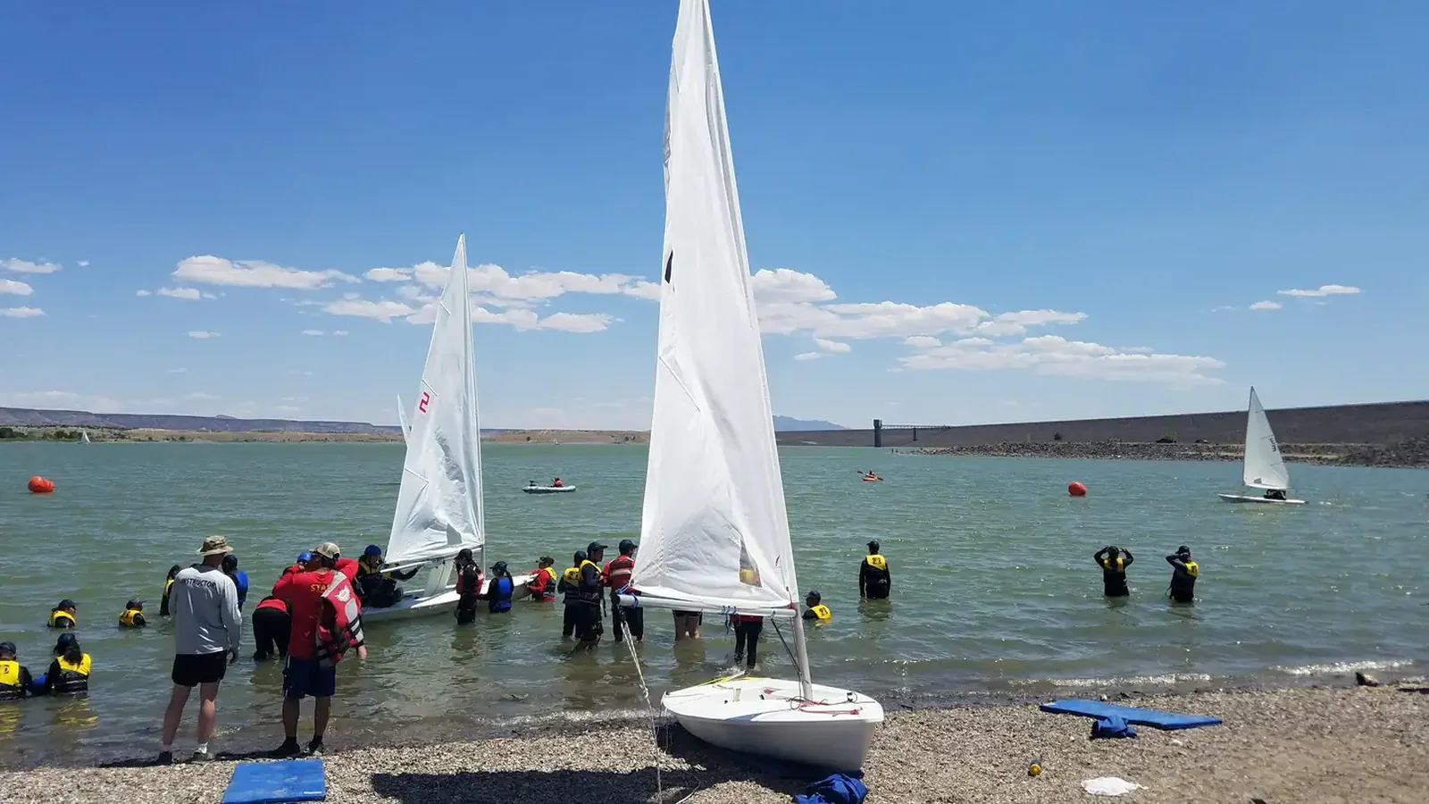 Two children and an adult paddle an aluminum sided canoe on a lake.
