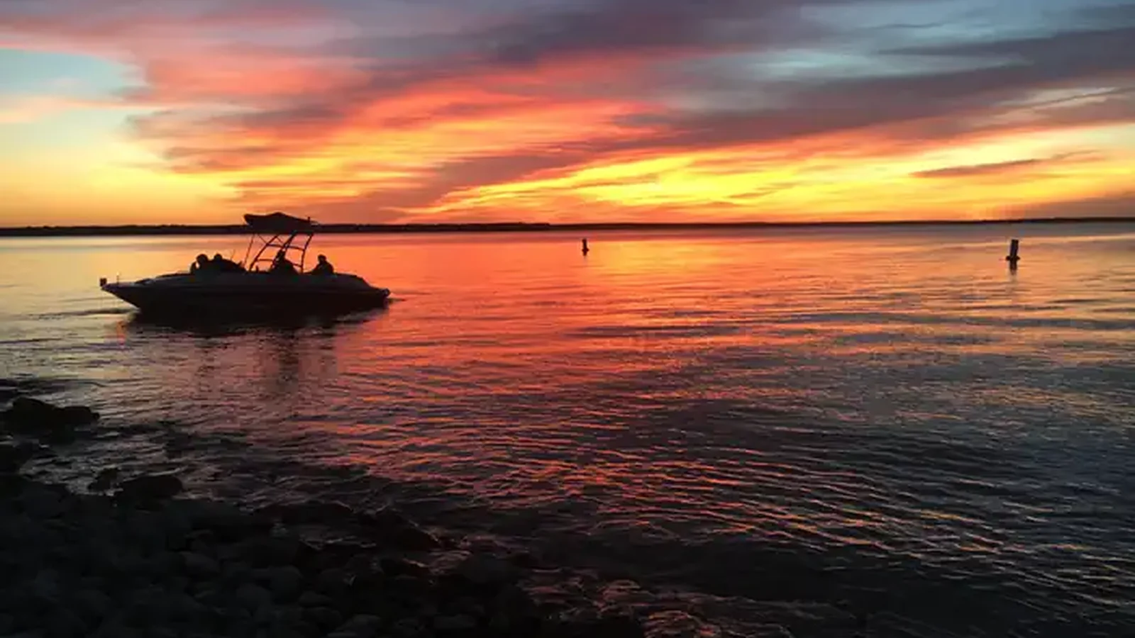 Wake boat silhouetted by sunset from beach at McCown Day Use Park