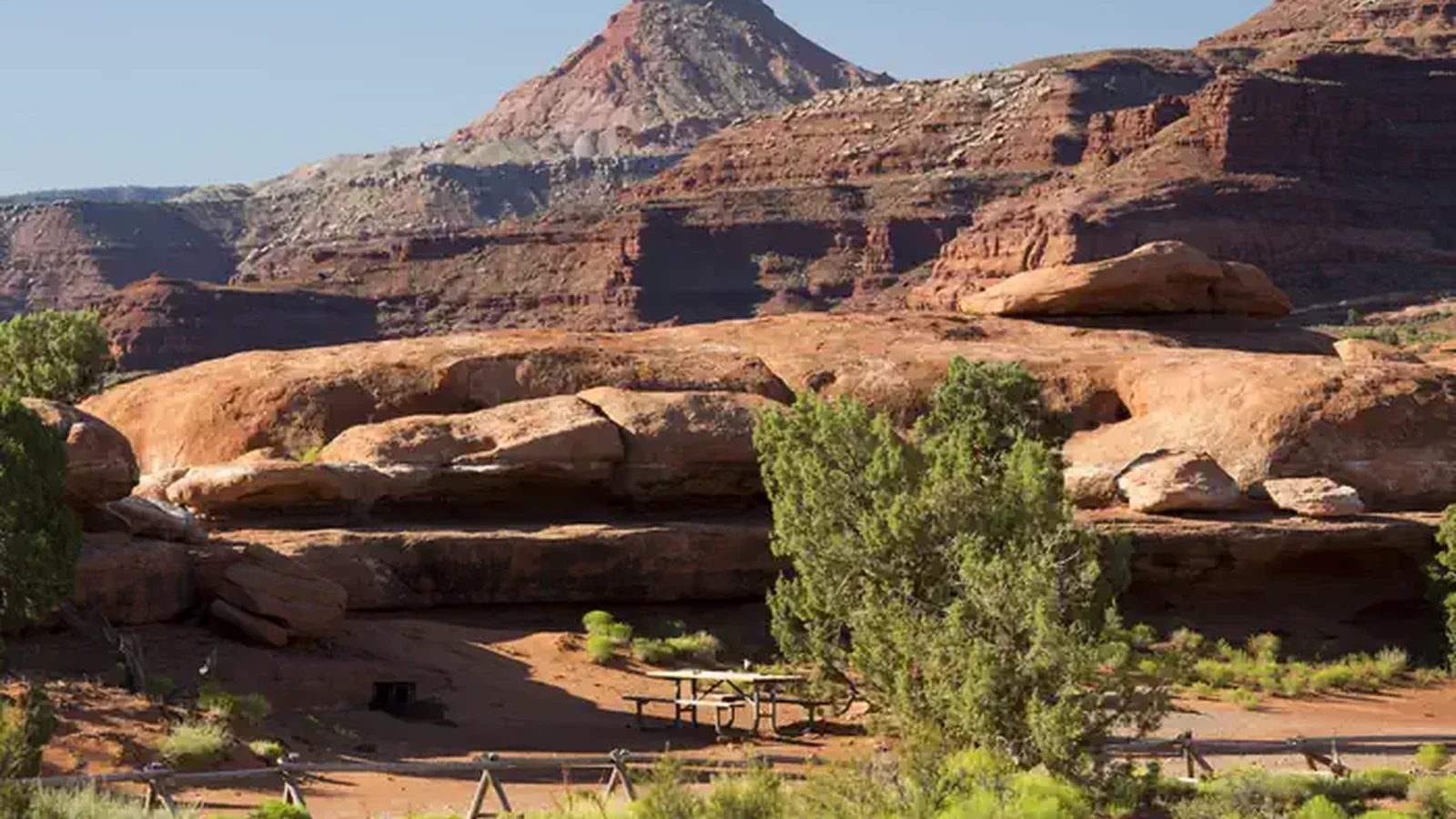 A picnic table adjacent to Hamburger Rock geologic feature with a Six Shooter peak in the background.