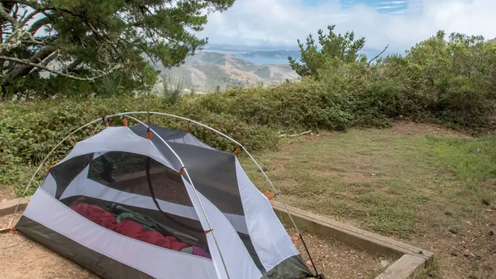 A tent in a tent pad at Hawk Campground, with a glimpse of the view in the background.