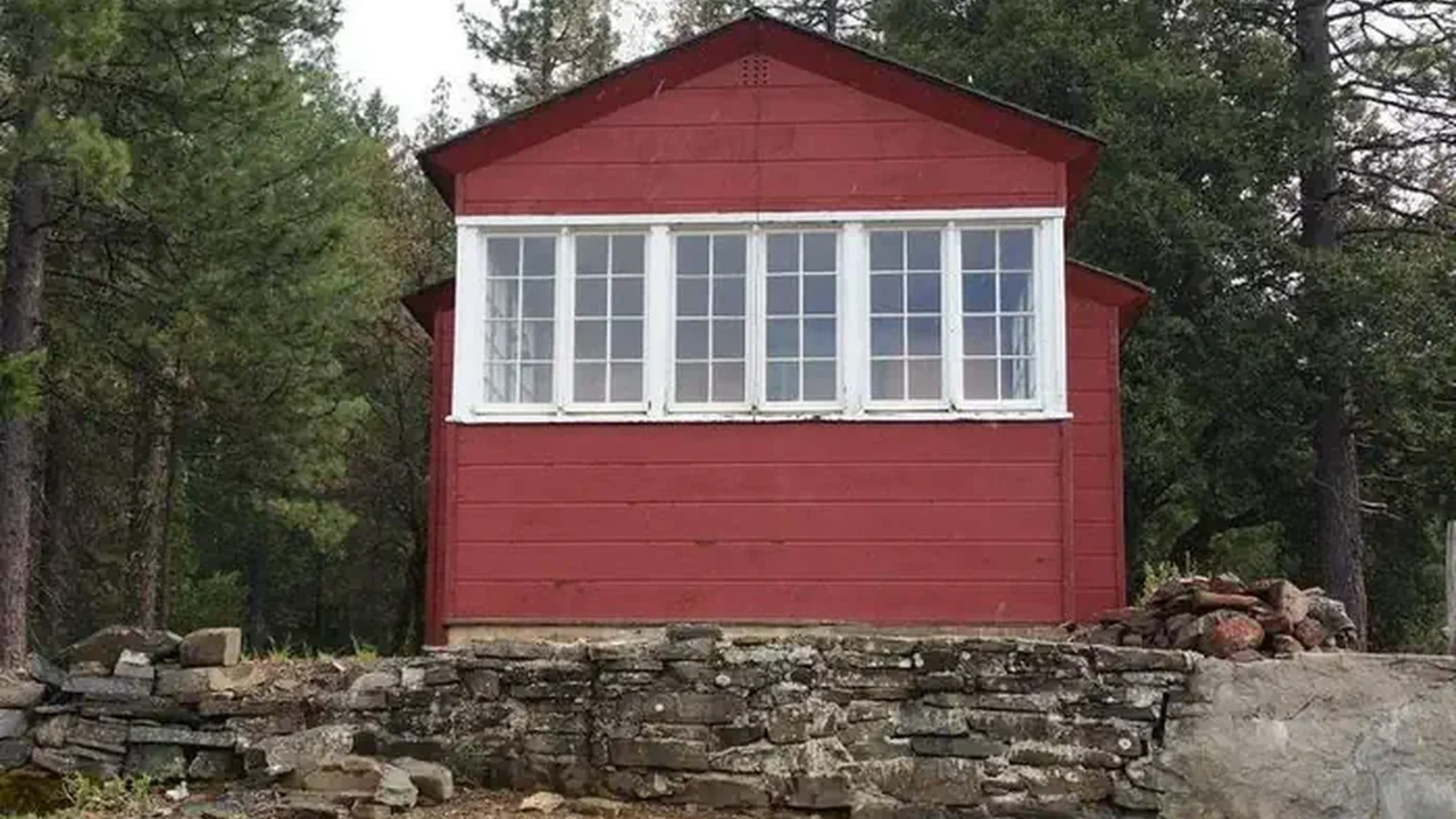 Back view of historic Post Creek Guard Station, red cabin, with white trim around windows.