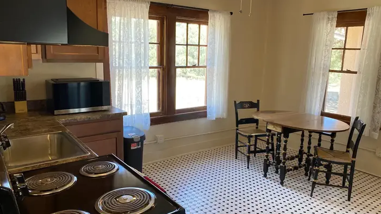 Kitchen table with two chairs, electric oven and 4 burner range, and micorwave.