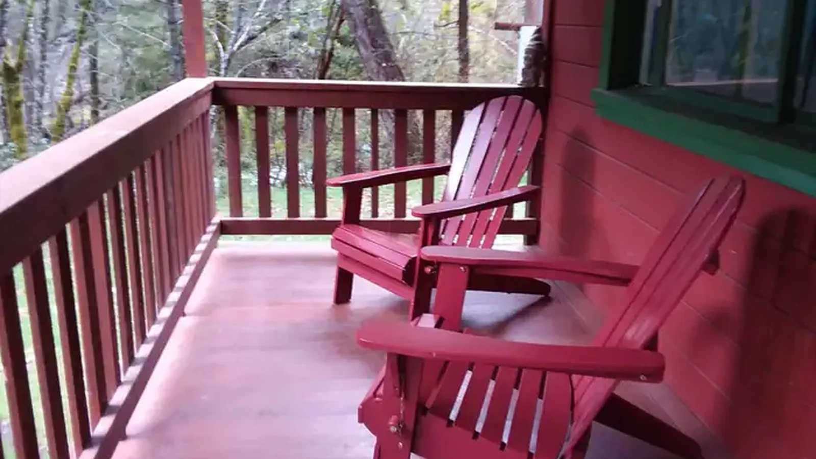 Front porch and two red Adirondack of red cabin.