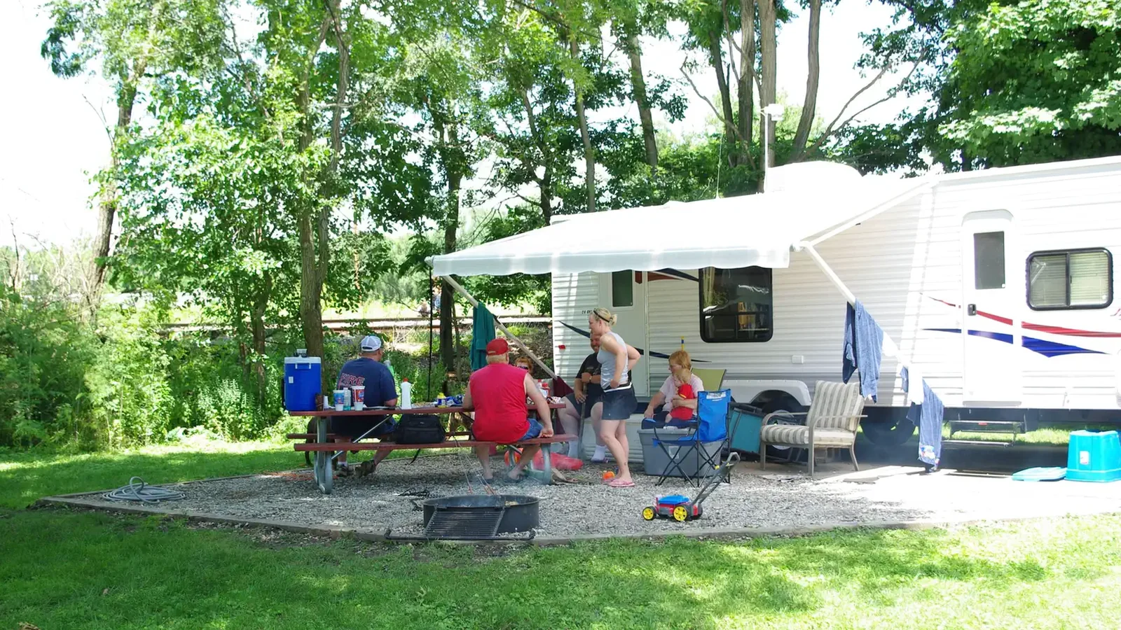 Campers visiting at campsite around picnic table.
