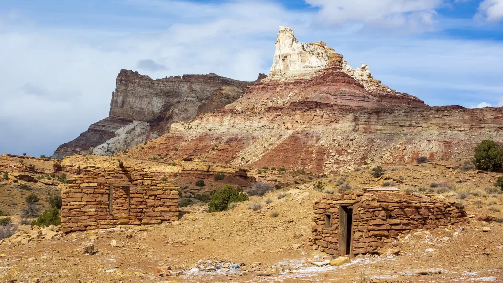 Stone cabin ruins with a sandstone butte in the background