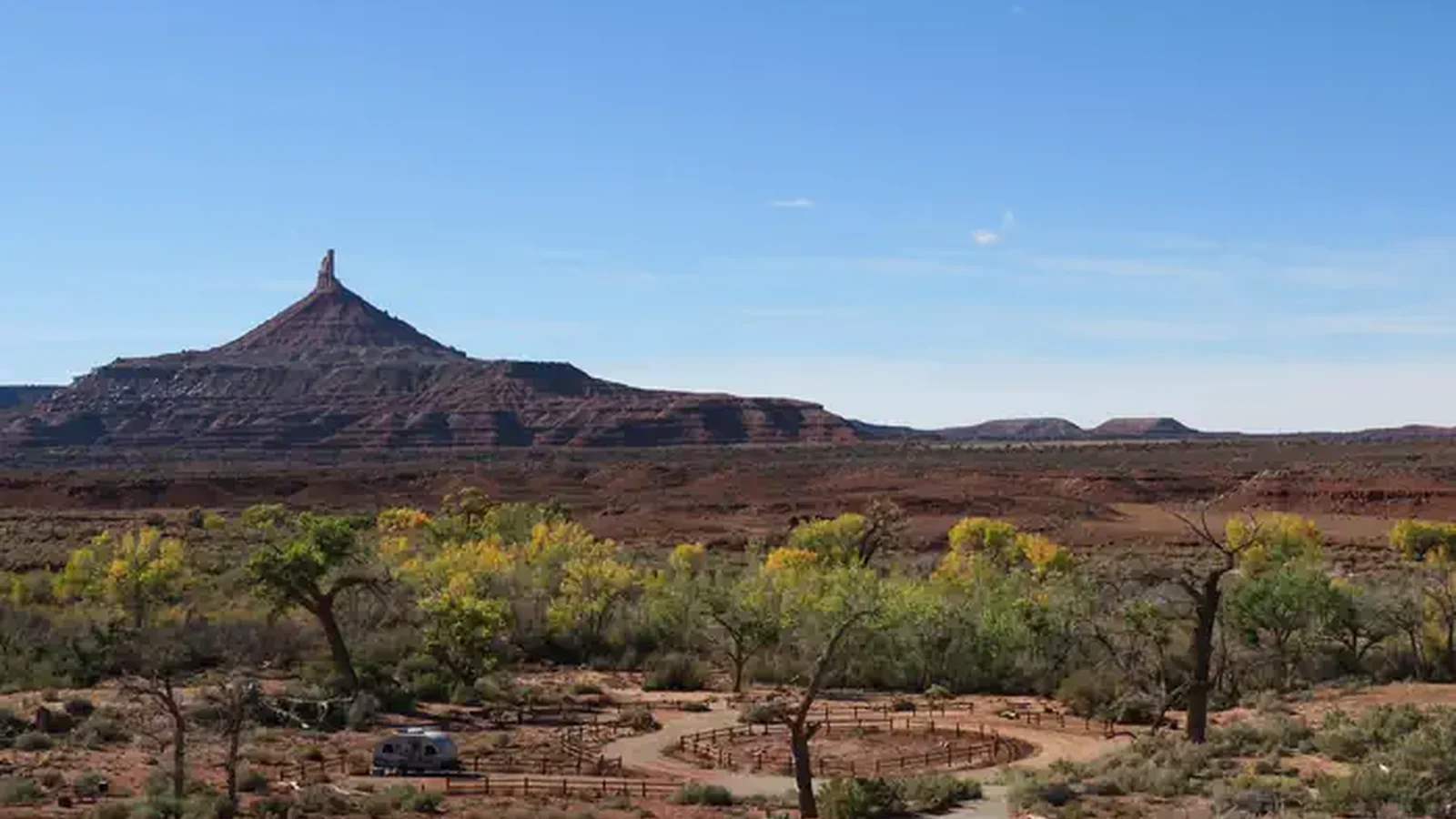 Panoramic view of the desert campground with a ribbon of cottonwood trees and Six Shooter Peak in the background.