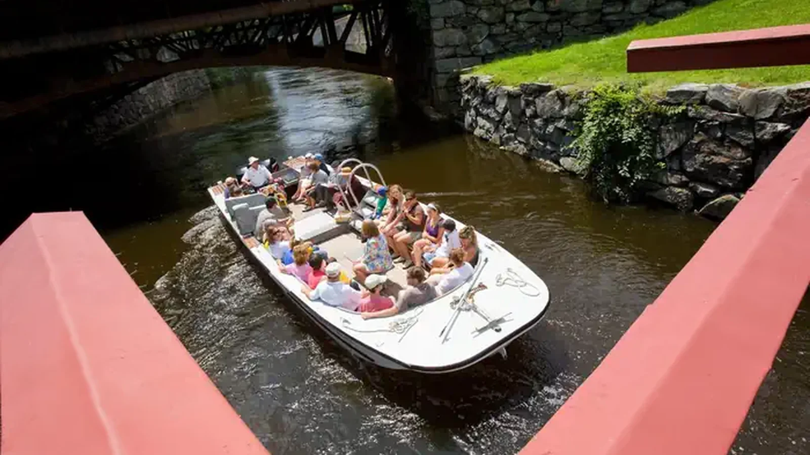 Group of visitors in an open top boat float on a canal
