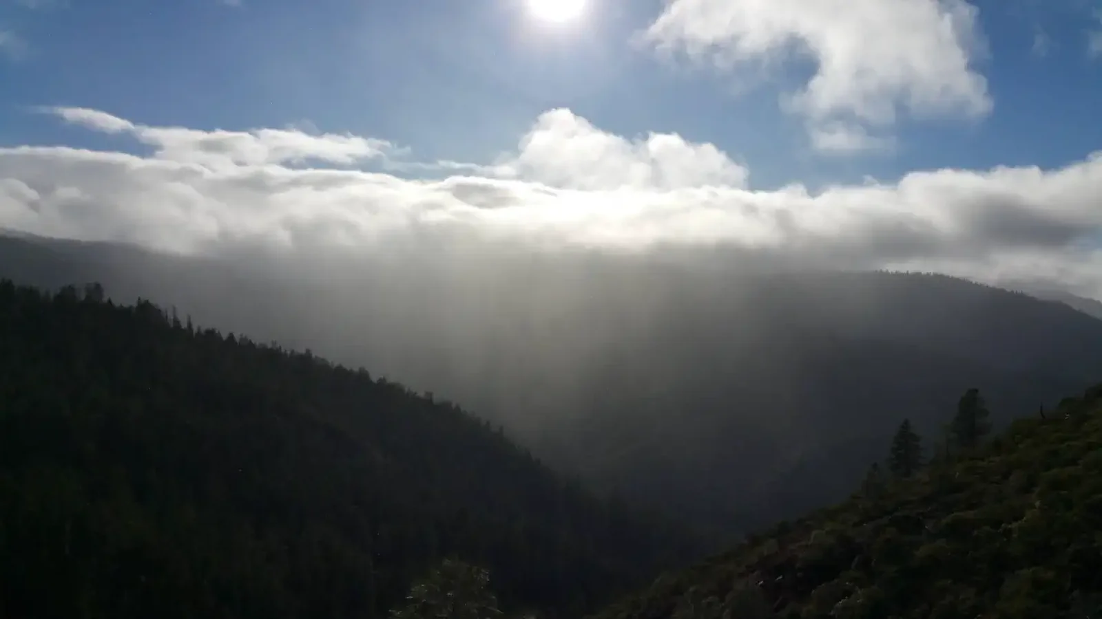 View of mountains, clouds, sun.