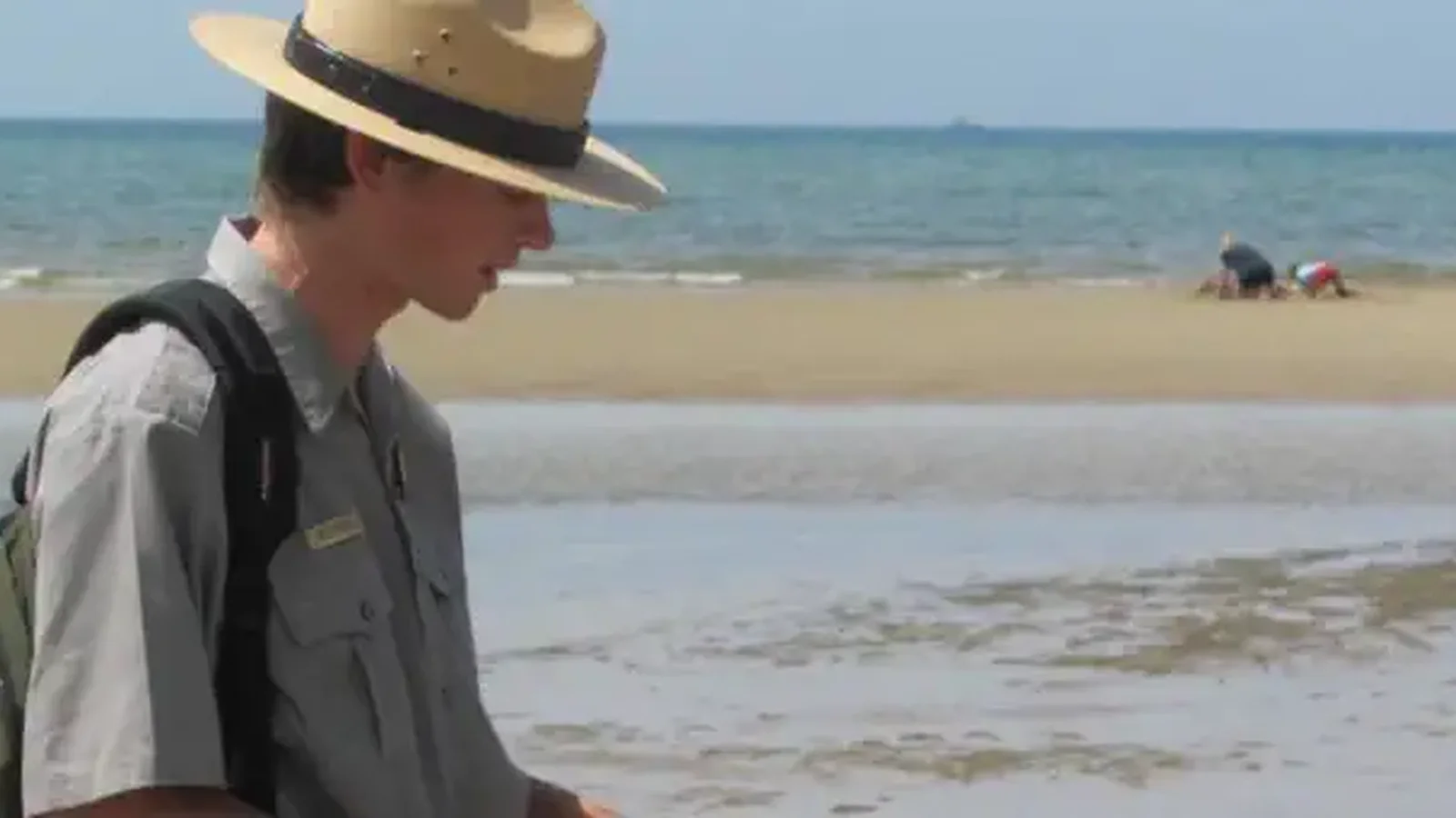 A young boy runs out onto tidal flats behind a ranger looking for beach life.