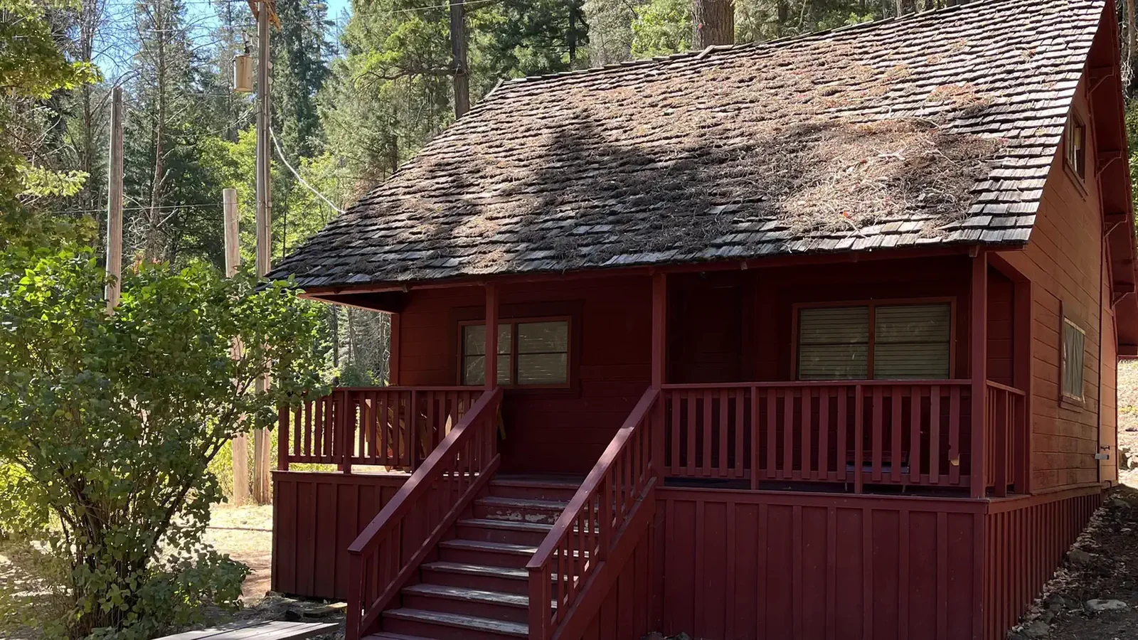 Portion of roof and porch of old, red cabin.