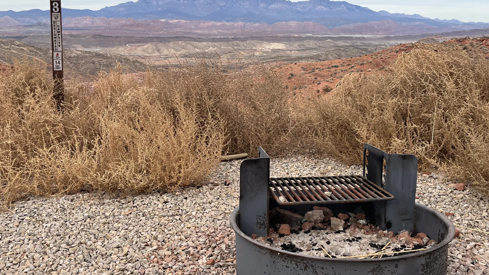 Graveled campsite against a backdrop of rolling red dirt hills and the Pine Valley Mountains.