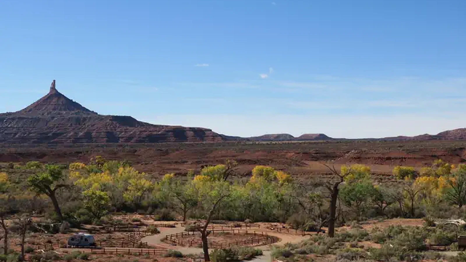 Panoramic view of the desert campground with a ribbon of cottonwood trees and Six Shooter Peak in the background.