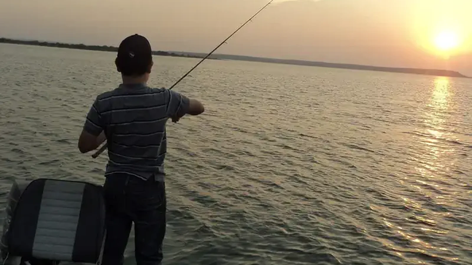 A young man fishing at sunset