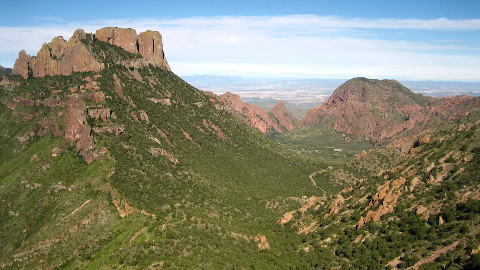 A view of Chisos Basin from the Lost Mine trail. Green vegetation with red mountains