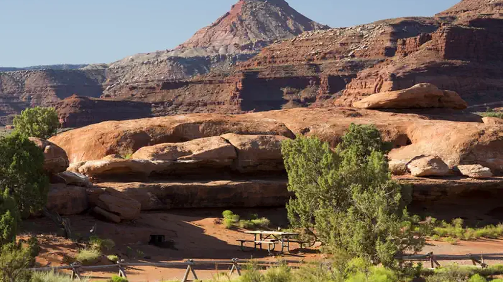 A picnic table adjacent to Hamburger Rock geologic feature with a Six Shooter peak in the background.