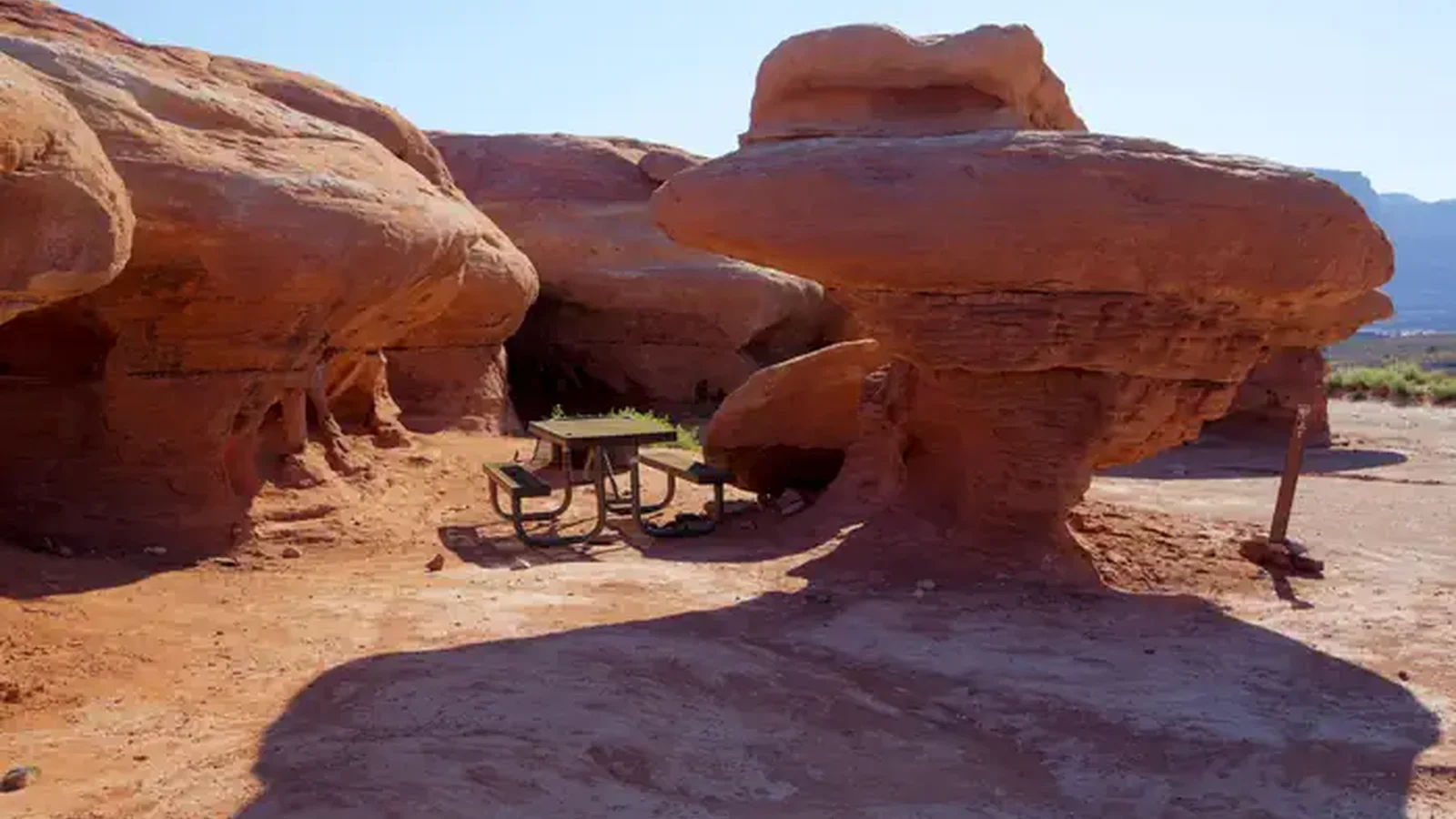 A picnic table underneath unique, overhanging red rock features.