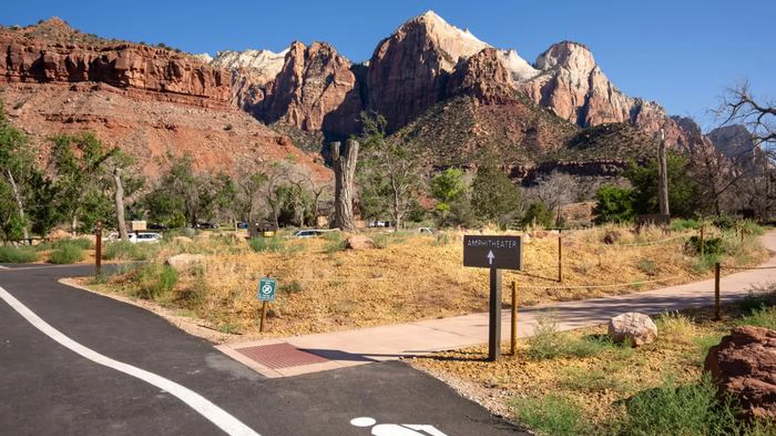 Pedestrian path winding through the campground with sheer, dramatic sandstone cliffs of Zion Canyon rising in the background.