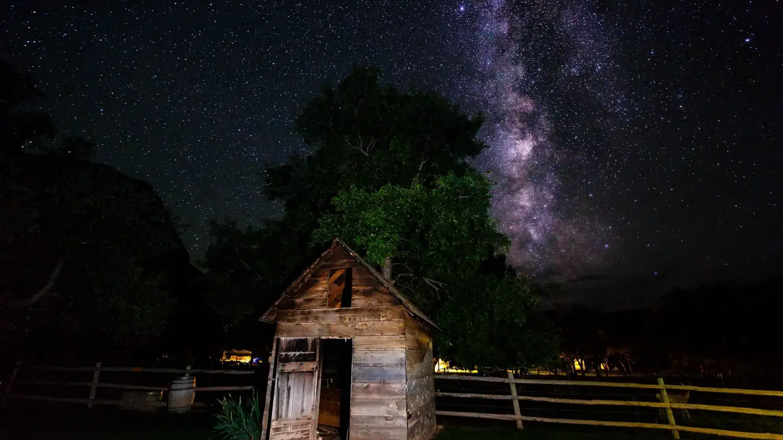 A purple starry night sky is featured behind a small building.