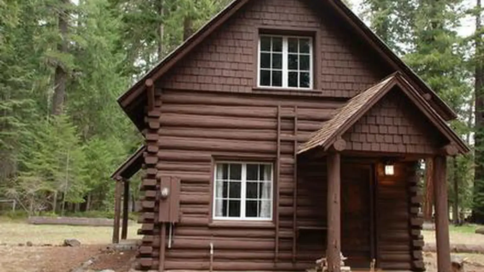 Log cabin with shake gable ends and covered entry way in conifer forest