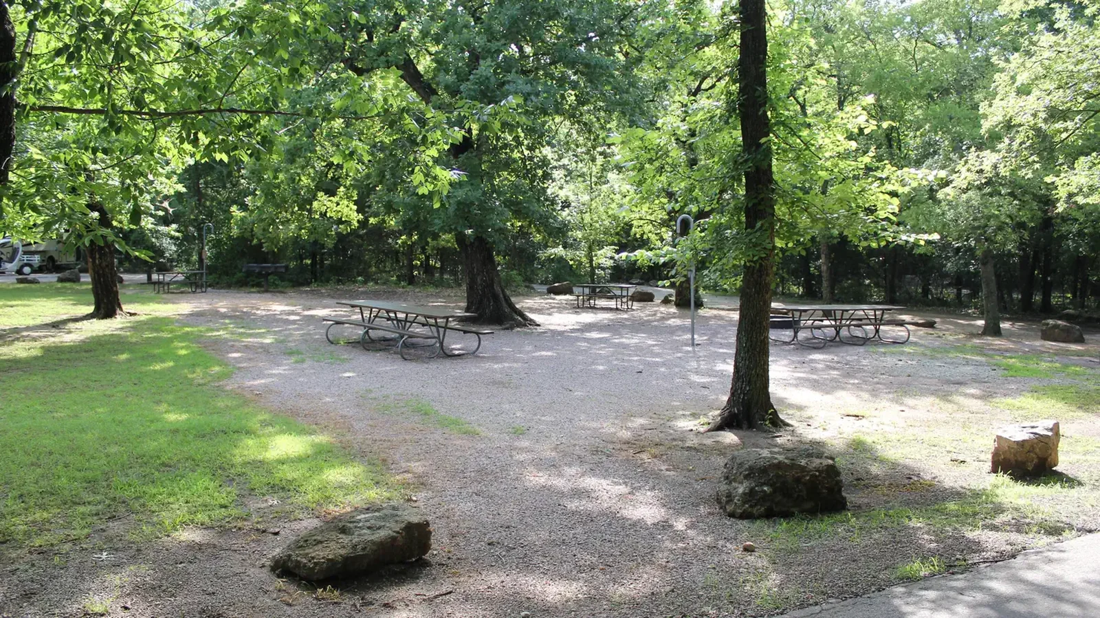 Several picnic tables beneath leafy trees that shade the Rock Creek Group Site