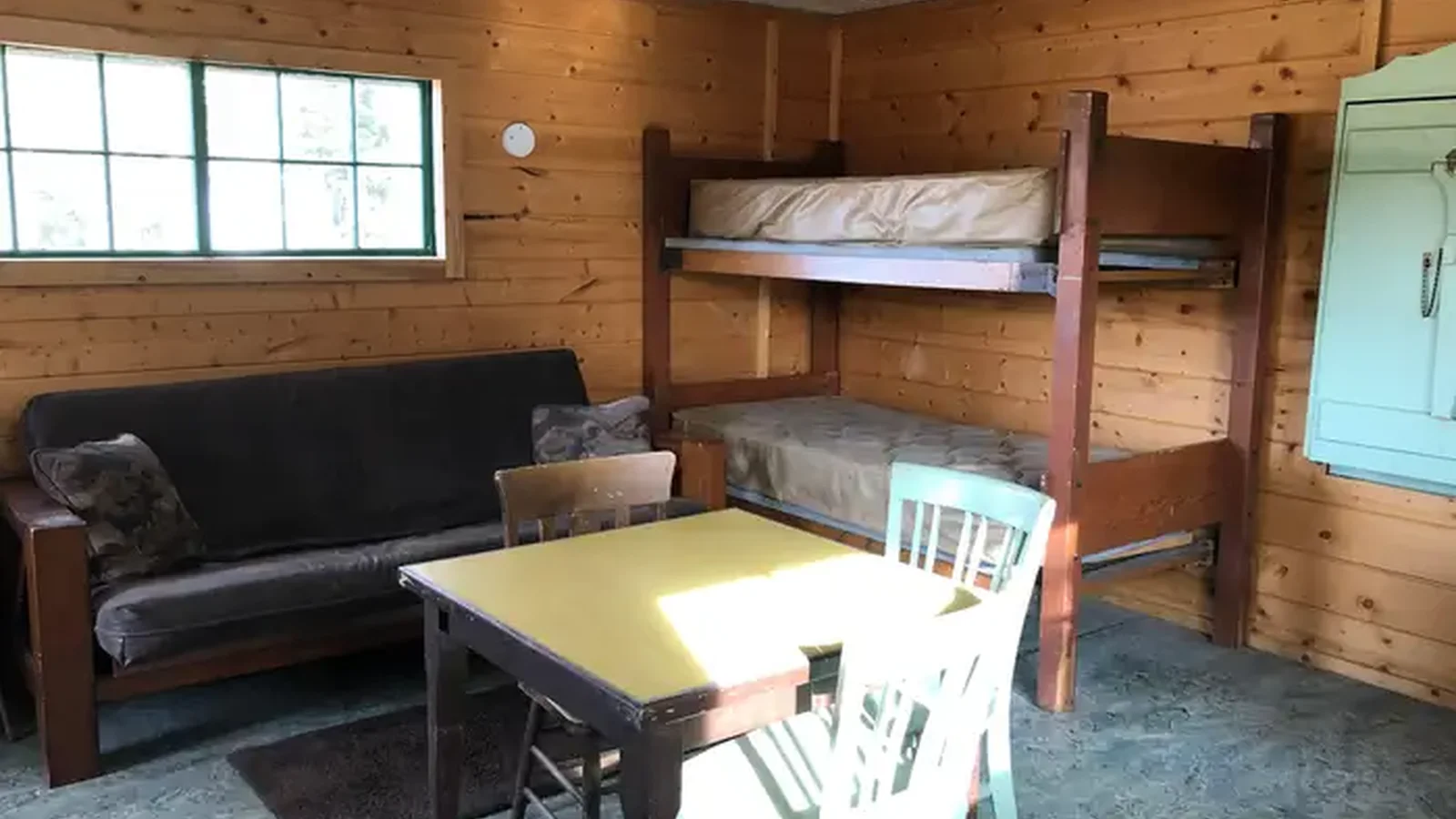 Cabin interior showing futon couch, bunkbeds and kitchen table