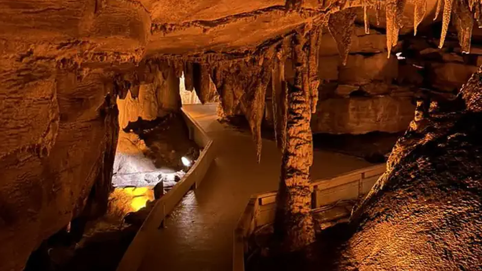 Sidewalk in the middle of the cave passageway with stalactites hanging over the trail