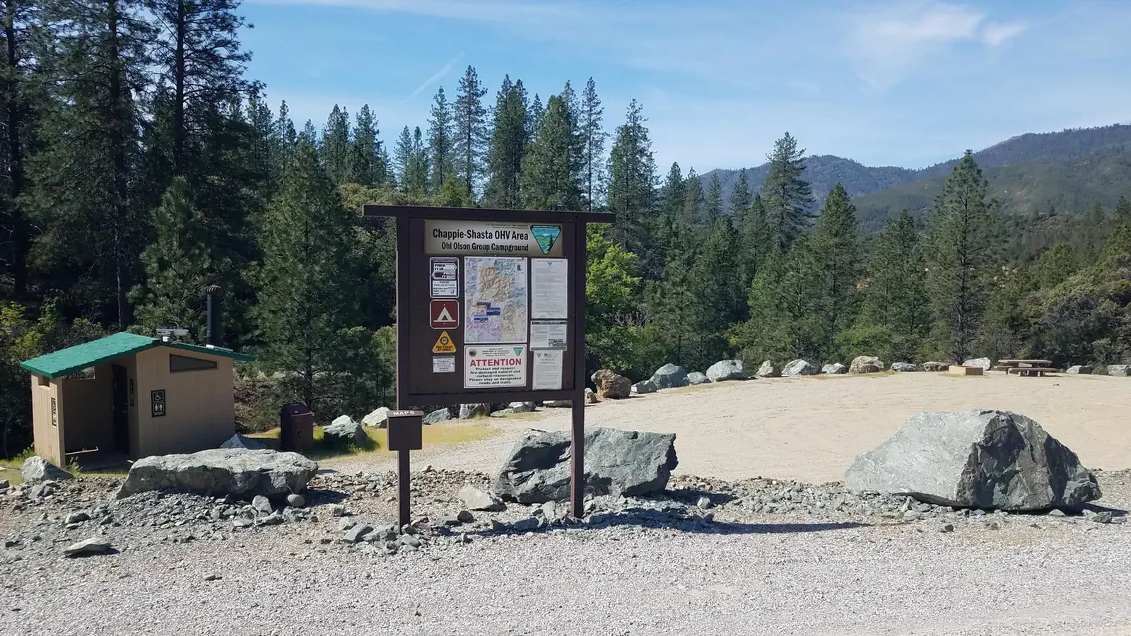 Informational kiosk, bathroom, and gravel camping area