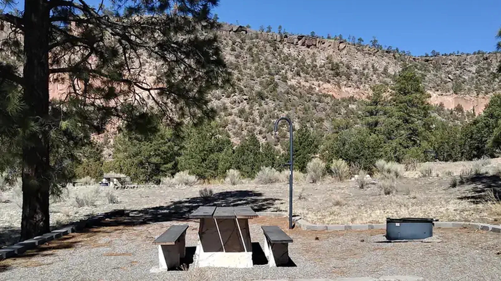 A picnic site with juniper, pines, and a mesa in the background.