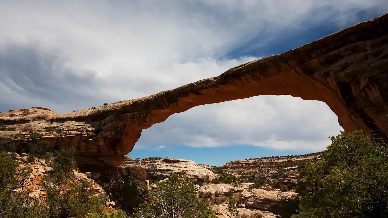 Owachomo Natural Bridge under a blue sky and cumulus clouds