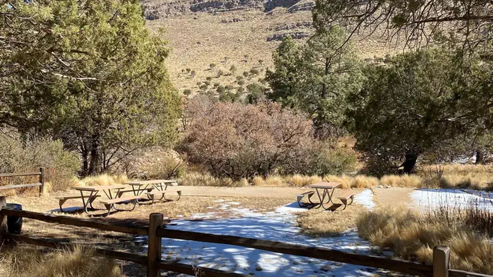 Dog Canyon Group Campsite with two tent pads delineated with landscape timbers and filled with fine crushed gravel. Three picnic tables are located in an open grassy area for groups to gather.